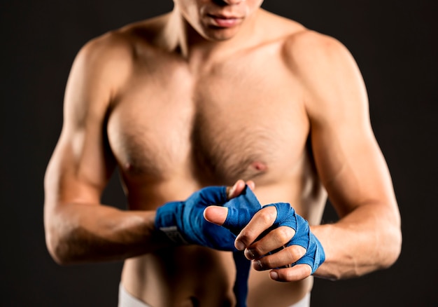 Free photo male boxer putting on protection for hands