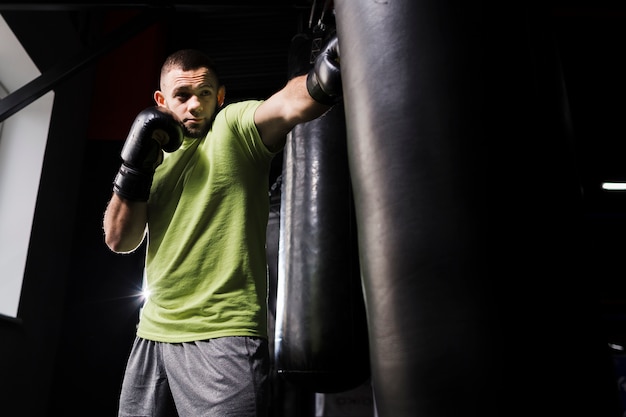 Male boxer in t-shirt practicing in protective gloves