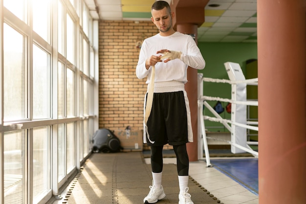 Male boxer wrapping his hands before training in the boxing ring