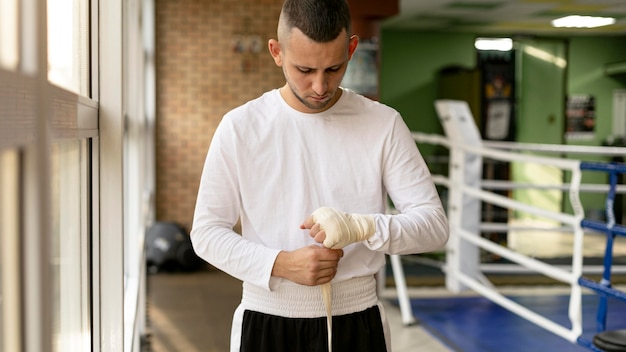 Male boxer wrapping his hands before training in the ring with ribbon