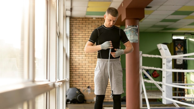 Male boxer wrapping his hands before training in the ring