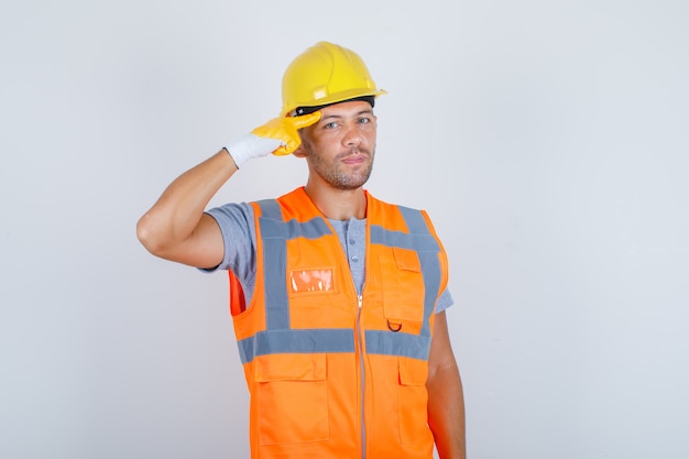 Generatore maschio che gesturing con il dito contro la tempia in uniforme, casco, vista frontale guanti.