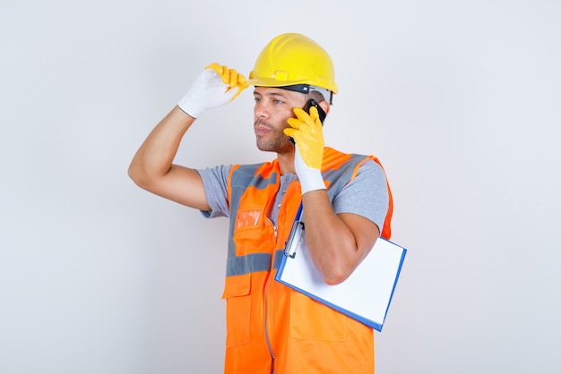 남성 작성기 유니폼, 장갑, 전면보기에 헬멧에 손으로 전화 통화.