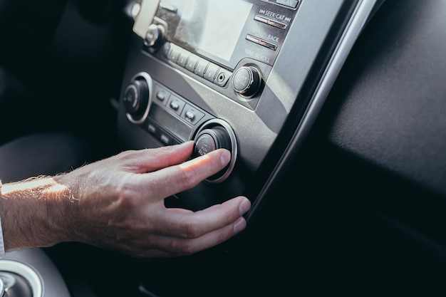 Male car driver tweaks air conditioner control close up photo