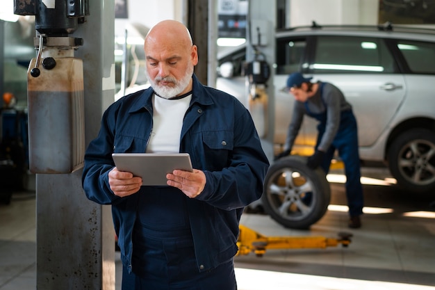 Male car mechanic using tablet device in the car repair shop