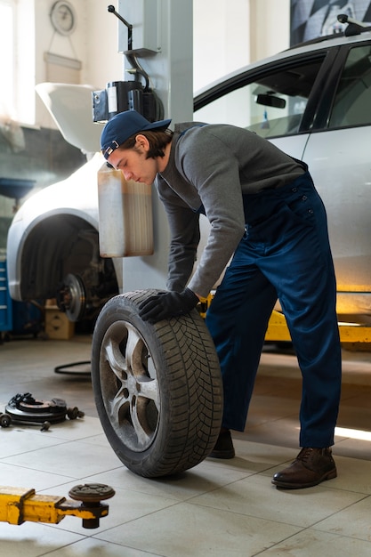 Meccanico di automobile maschio che lavora nell'officina di riparazione dell'automobile