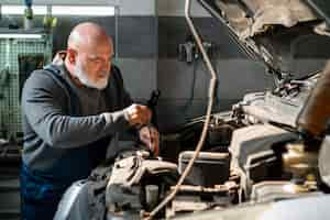 Foto gratuita meccanico di automobile maschio che lavora nell'officina di riparazione dell'automobile