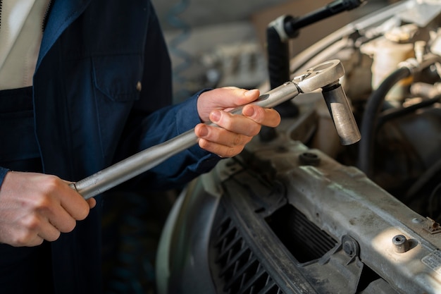 Foto gratuita meccanico di automobile maschio che lavora nell'officina di riparazione dell'automobile