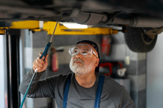 Foto gratuita meccanico di automobile maschio che lavora nell'officina di riparazione dell'automobile