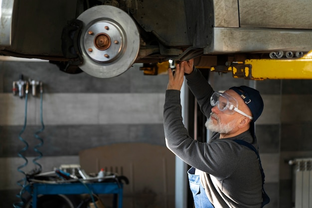 Foto gratuita meccanico di automobile maschio che lavora nell'officina di riparazione dell'automobile