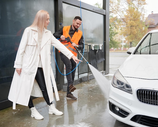 Male car washer cleaning auto under supervision of owner