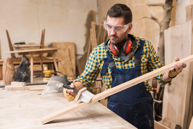 male carpenter cleaning the plank with brush