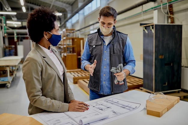 Free photo male carpenter explaining design plans to african american female manager at production facility