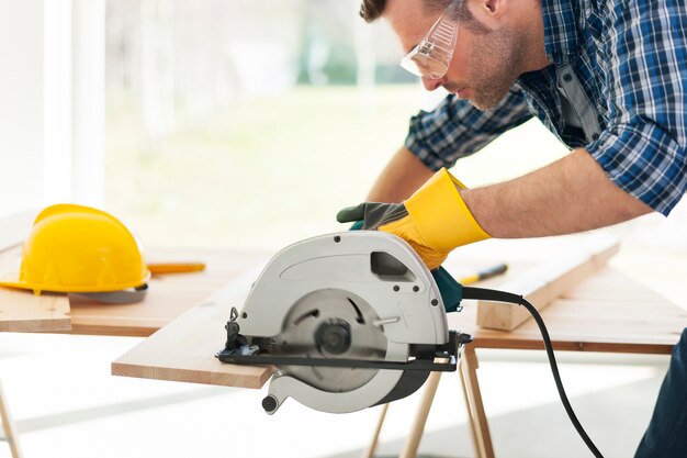 Male carpenter sawing wooden boards
