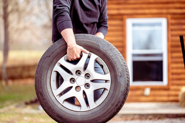 新しい車のタイヤを運ぶ男性