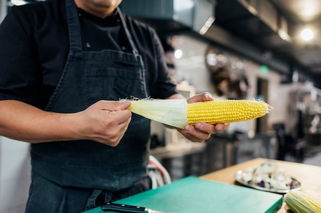 Free photo male chef cleaning corn cob