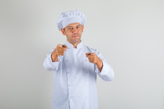 男性シェフが帽子とカメラで人差し指を指して自信を持って料理をする