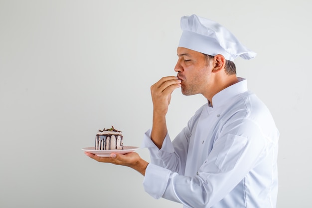 남자 요리사 요리사 케이크를 들고 모자와 유니폼에 맛있는 제스처를 만들기