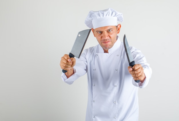 Free photo male chef cook holding kitchen knives in uniform and hat and looking confident