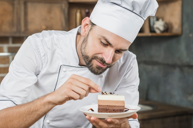 Мужской шеф-повар, украшающий вкусный десерт на тарелке