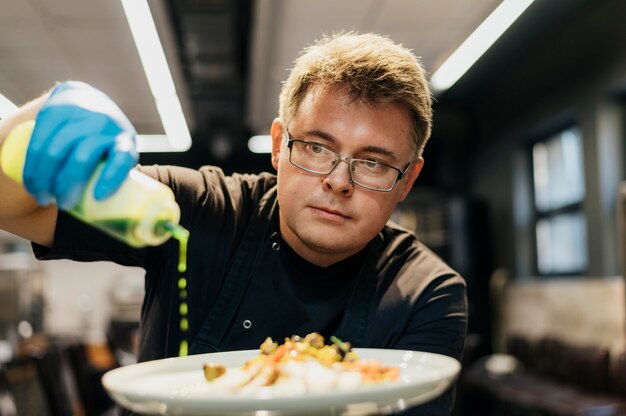 Male chef garnishing dish with sauce