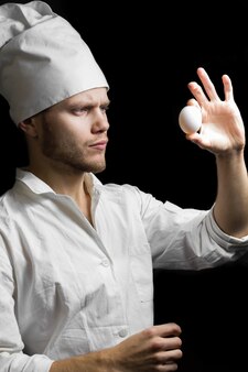 Мужчина повар держит яйцо в руке готовит яйца