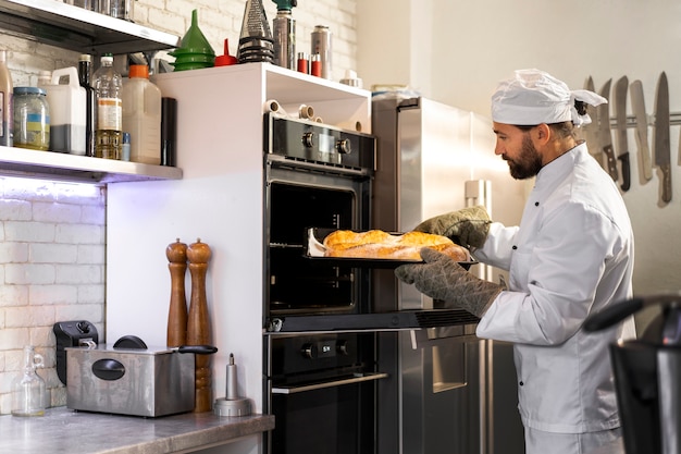 Foto gratuita chef maschio in cucina che cuoce il pane