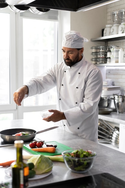 Free photo male chef in the kitchen cooking dish in a frying pan