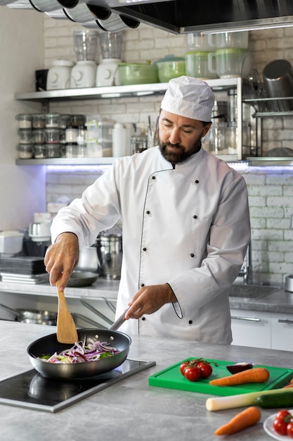 Foto gratuita cuoco unico maschio in cucina che cucina il piatto in una padella