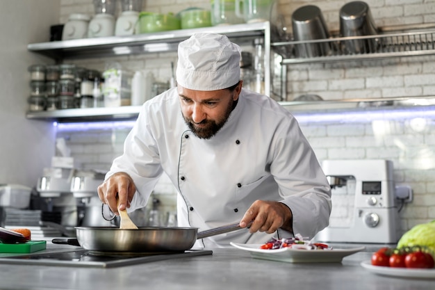 Free photo male chef in the kitchen cooking dish in a frying pan