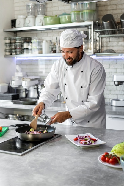 Free photo male chef in the kitchen cooking dish in a frying pan