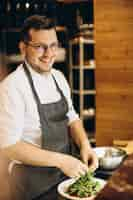 Free photo male chef at kitchen preparing salad rubbing cheese on top