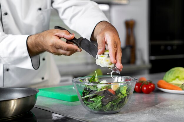 Male chef in the kitchen preparing salad