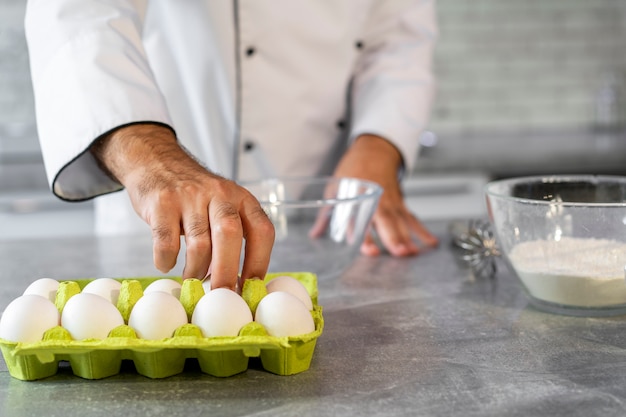 Foto gratuita cuoco unico maschio in cucina usando le uova per cucinare