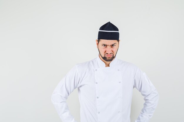 Male chef looking forward in white uniform and looking nervous , front view.