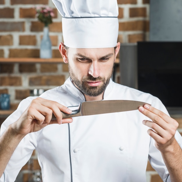Мужской шеф-повар смотрит на острый нож