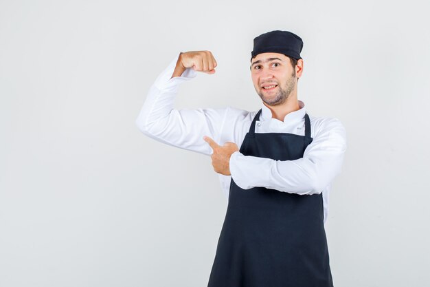 유니폼, 앞치마에 그의 근육에 손가락을 가리키는 남성 요리사 자신감을 찾고. 전면보기.