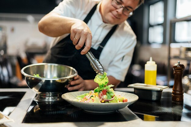 Шеф-повар-мужчина кладет салат на тарелку