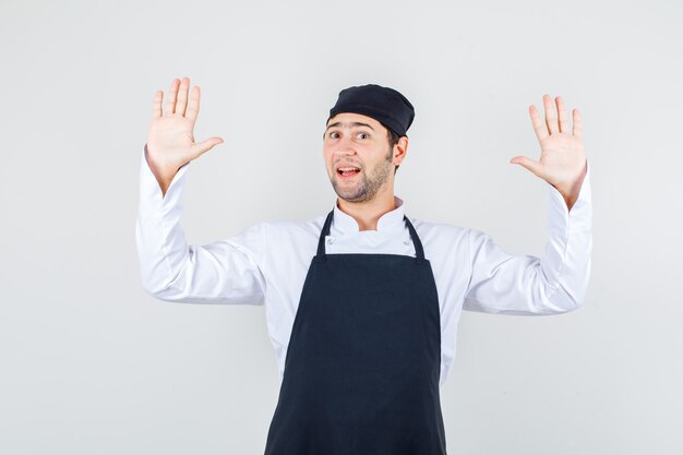 유니폼, 앞치마, 전면보기에서 항복에 손을 올리는 남성 요리사.