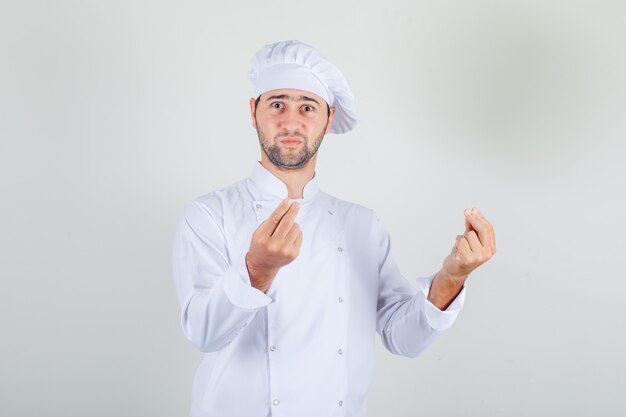 Шеф-повар-мужчина показывает жест руками в белой форме и выглядит смущенным