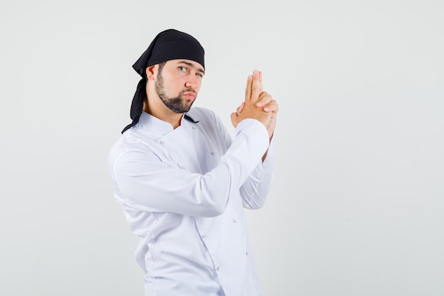 Foto gratuita cuoco unico maschio che mostra il gesto della pistola in uniforme bianca e sembra fiducioso, vista frontale.