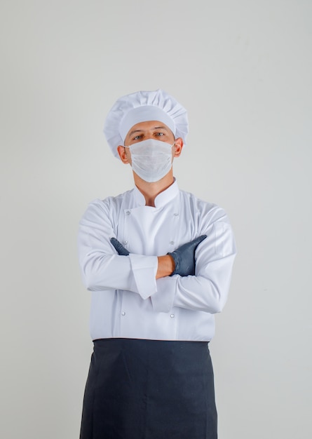 Free photo male chef standing with crossed arms in uniform, apron and hat and looking confident