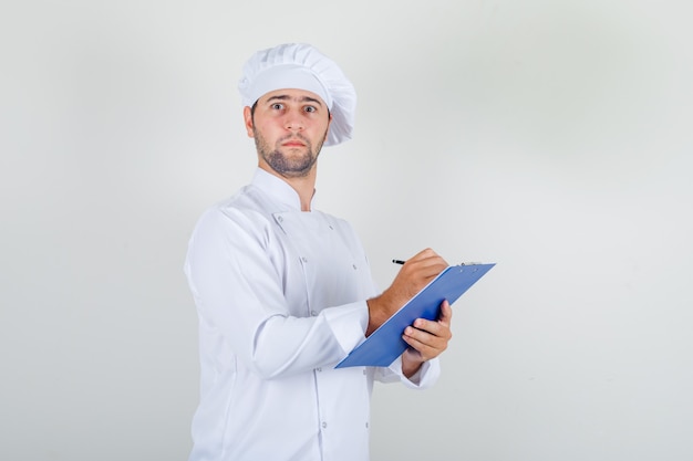 흰색 유니폼 클립 보드에 메모를하고 바쁜 찾고 남성 요리사