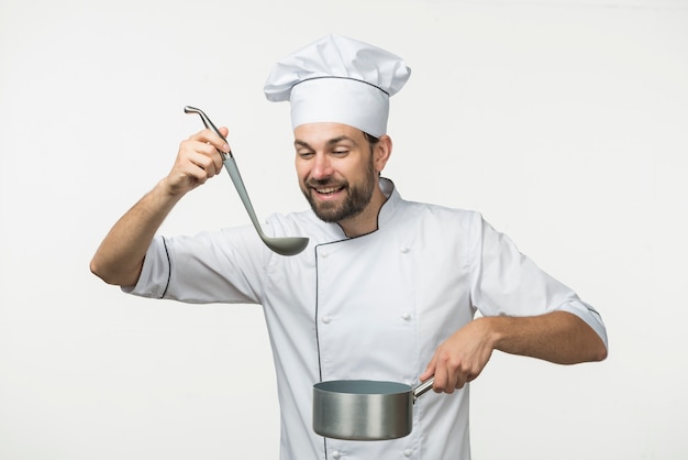 Мужской шеф-повар, дегустация суп в ковше на белом фоне