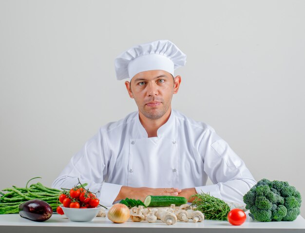 Male chef in uniform and hat sitting in kitchen