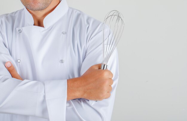 Male chef in uniform holding whisk with crossed arms