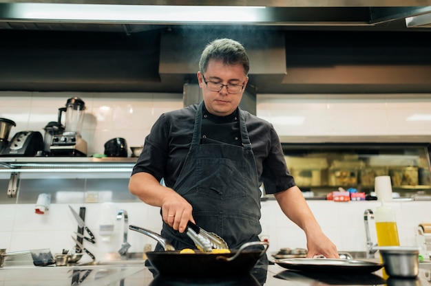 Free photo male chef with apron cooking pasta