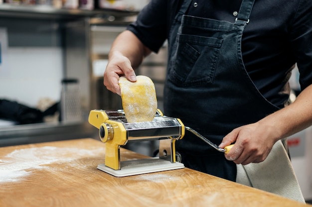 Male chef with apron rolling pasta dough