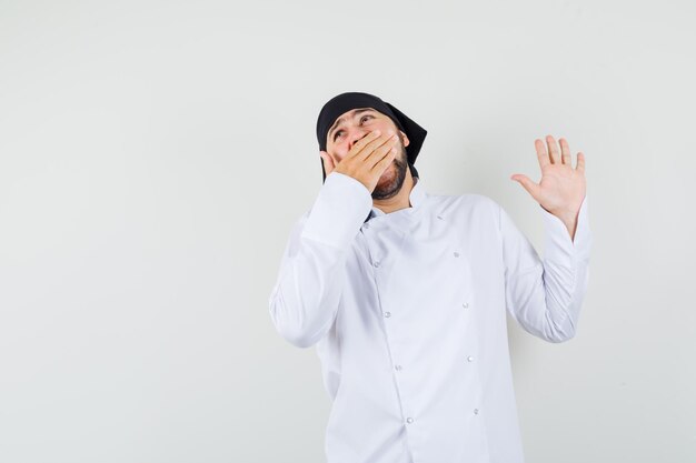 Male chef yawning in white uniform and looking sleepy. front view.