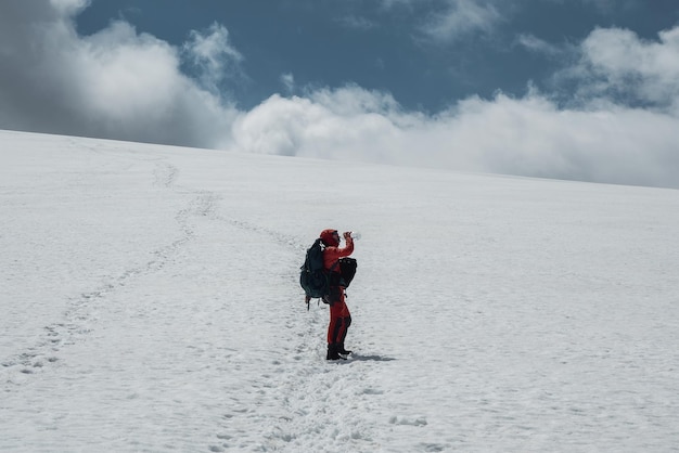 남성 산악인은 등반하는 동안 눈 덮인 산비탈에서 물을 마신다.